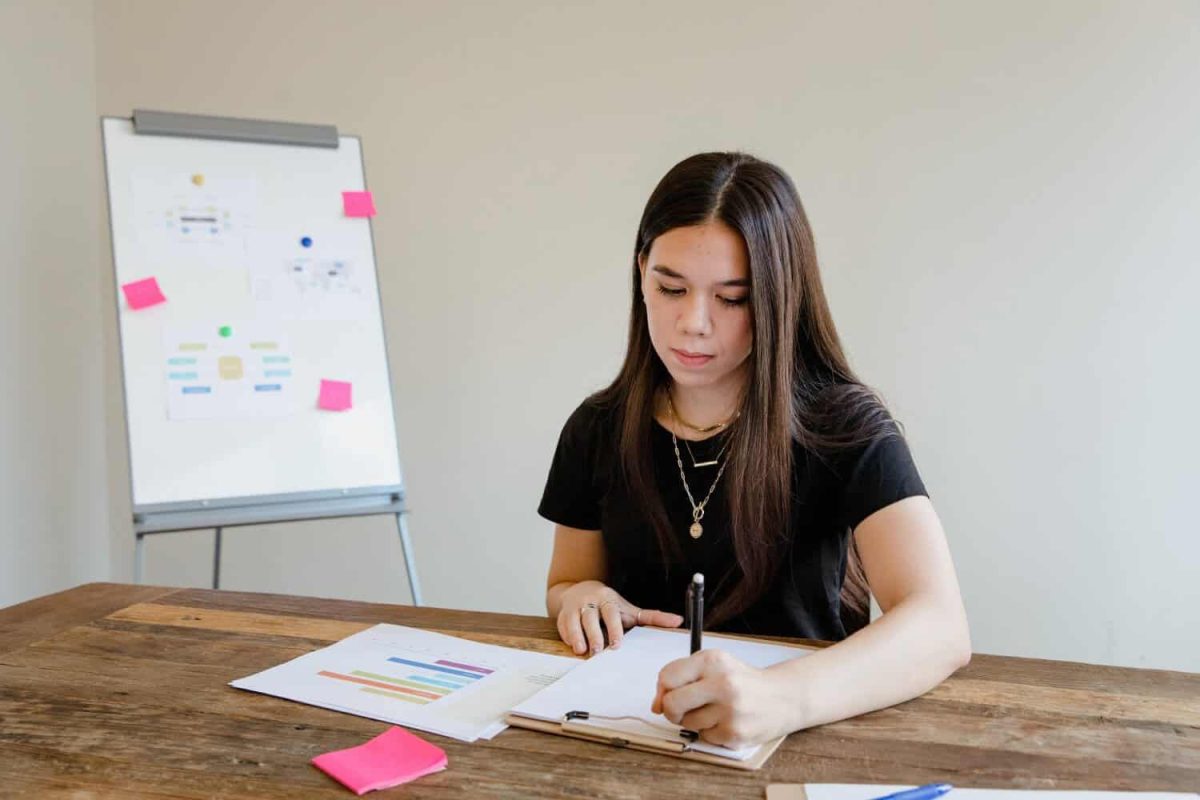 Woman working on custom signs and vehicle wraps at a desk in an office.